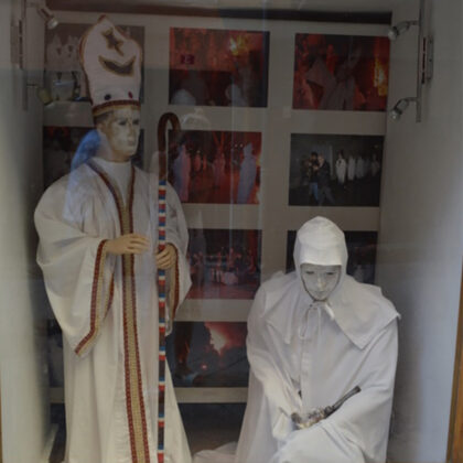 à gauche, une vitrine où sont exposés des mannequins des faux pénitents blancs